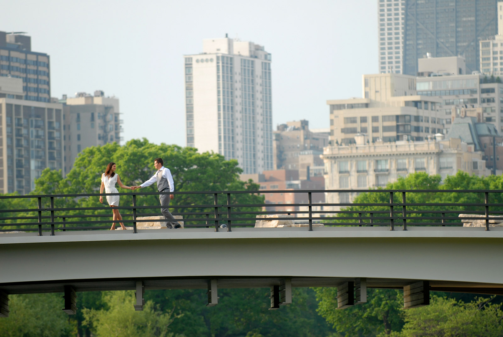 Engaged couple holding hands on bridge in Lincoln Park Zoo South Pond