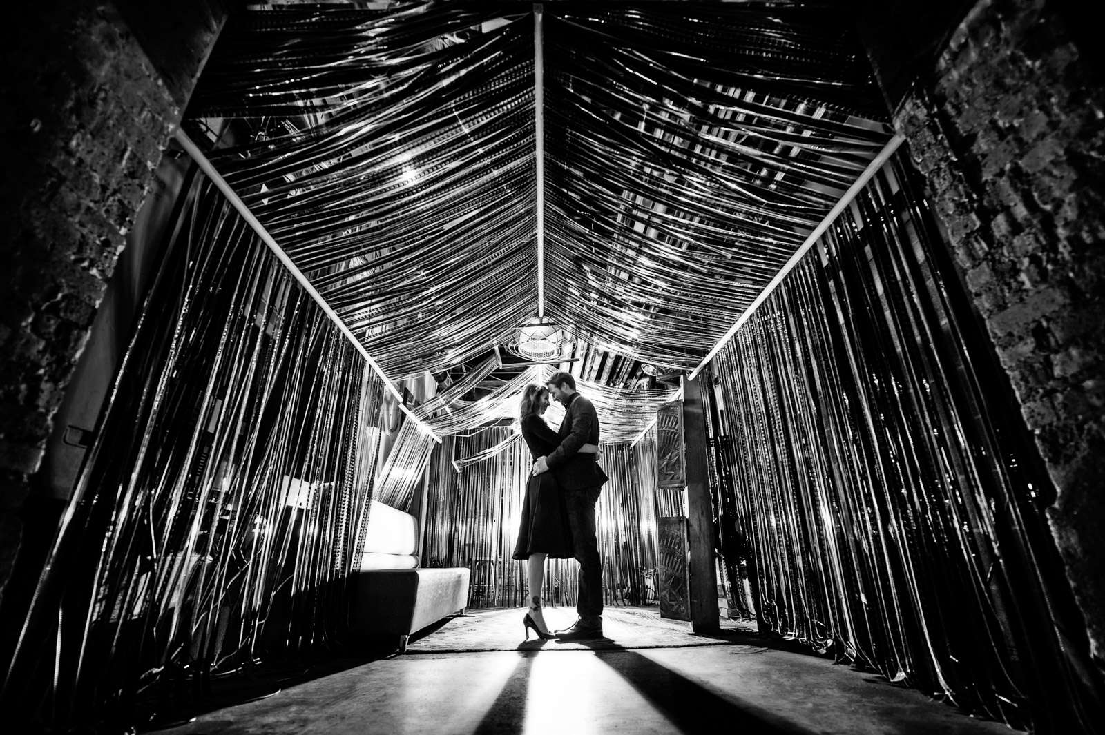 Engagement Session photo in black and white of couple underneath film strips at Salvage One in Chicago