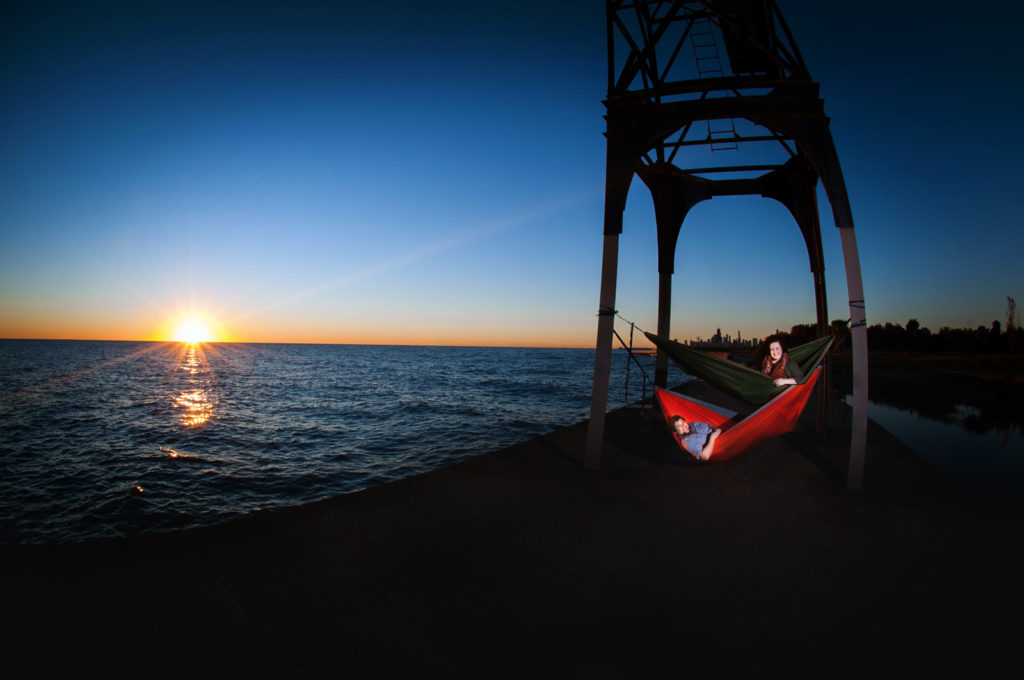 Laying in hammocks at sunrise on Lake Michigan in Chicago during their engagement session