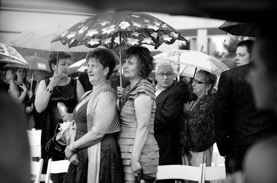 Wedding Guests under umbrella in rain at ceremony 
